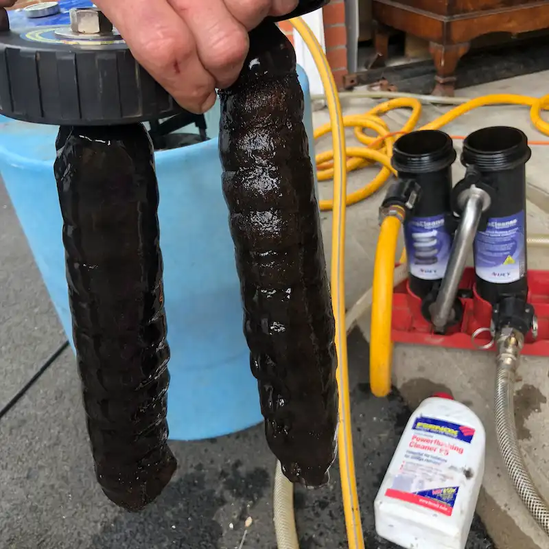 Black magnetic sludge collected on two filter magnets during heating-system cleaning