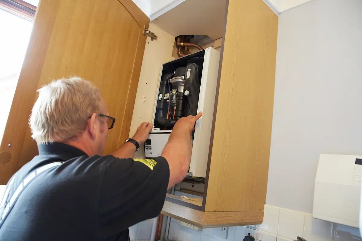 Vector Heat engineer working on a gas boiler inside a kitchen cupboard