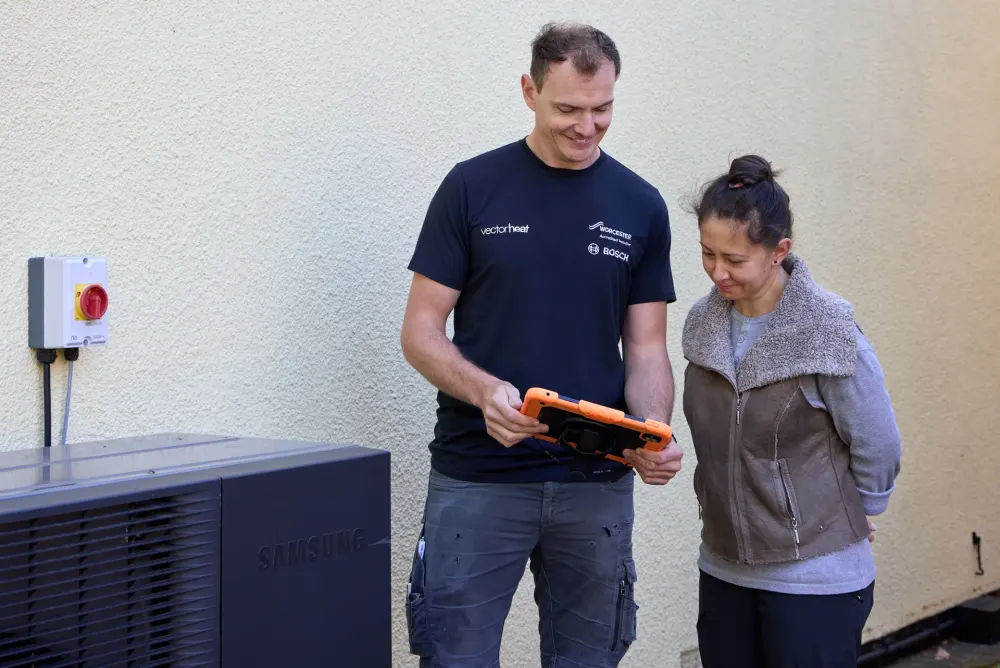 Vector Heat engineer looking at an iPad with a customer beside a Samsung heat pump