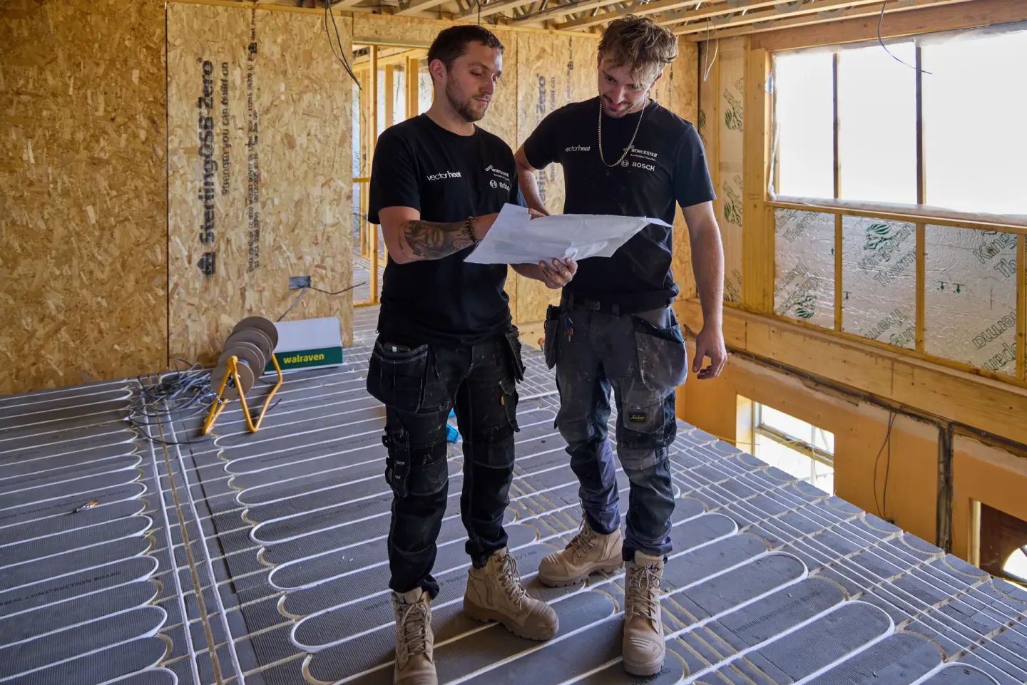Vector Heat engineers checking heating plans on site above installed underfloor heating pipework