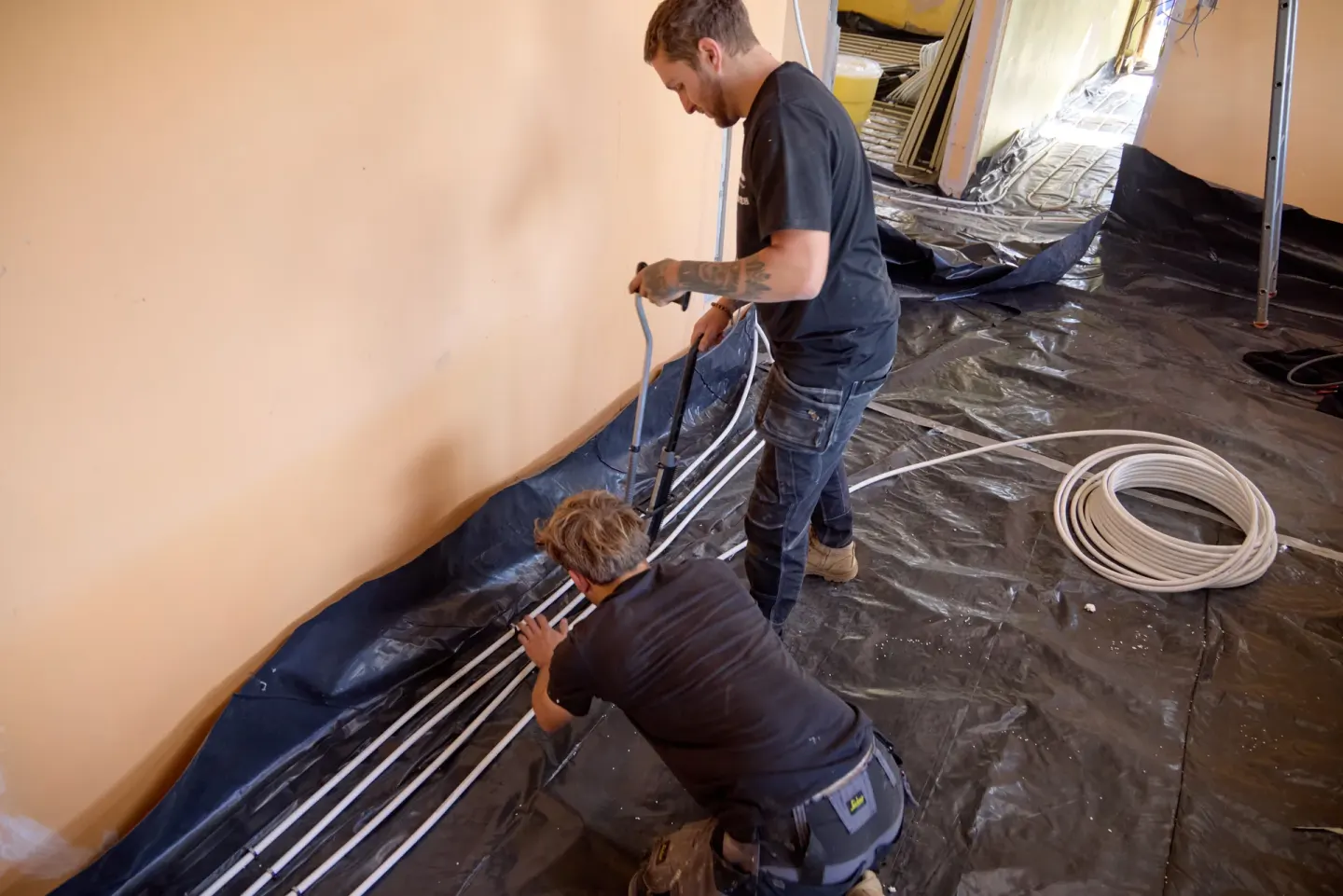 Vector Heat engineers installing wet underfloor heating pipes with a stapler