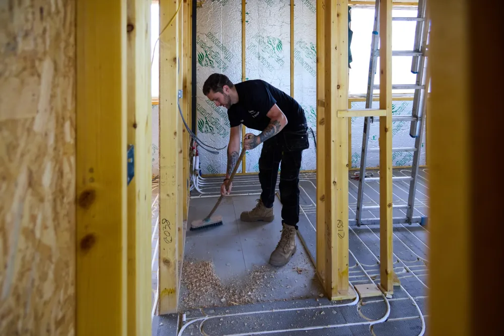 Vector Heat engineer sweeping up beside newly installed underfloor heating on site