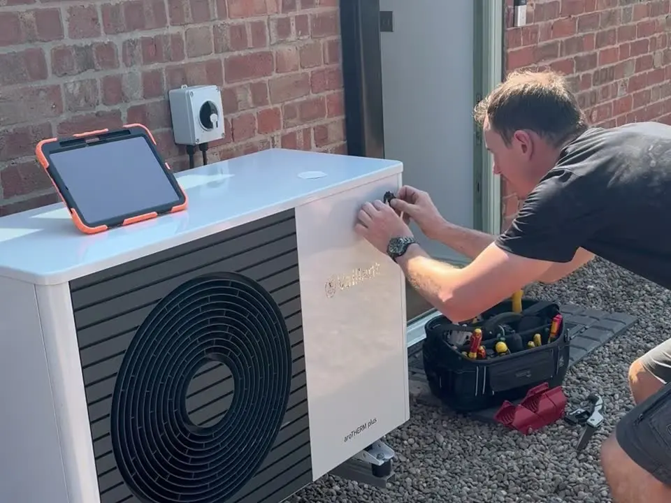 Liam fitting a Heat Geek sticker to a Vaillant aroTHERM Plus heat pump