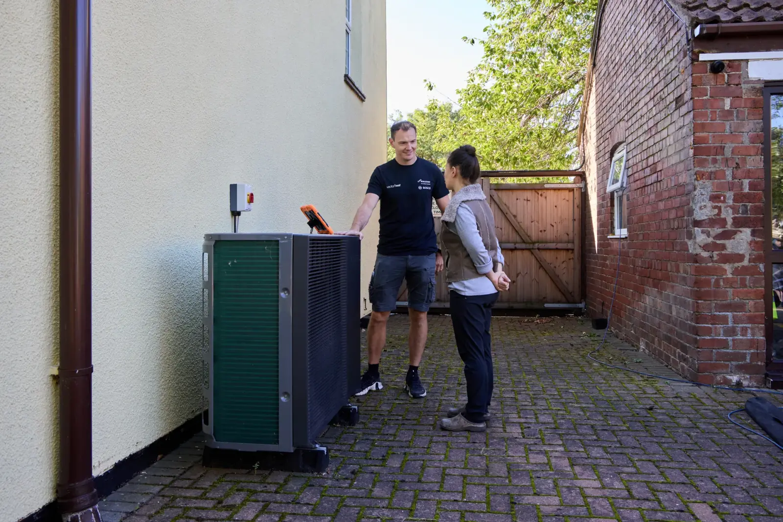 Vector Heat engineer talking with a customer beside a Samsung R290 16 kW heat pump