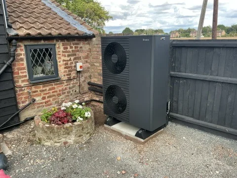 Twin-fan Vaillant aroTHERM plus 12 kW Series 8 heat pump installed beside an old brick home