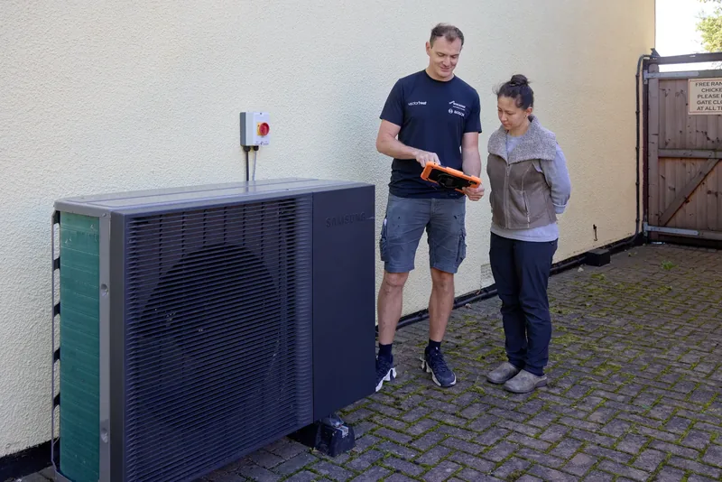 Vector Heat engineer looking at an iPad with a customer beside a Samsung heat pump