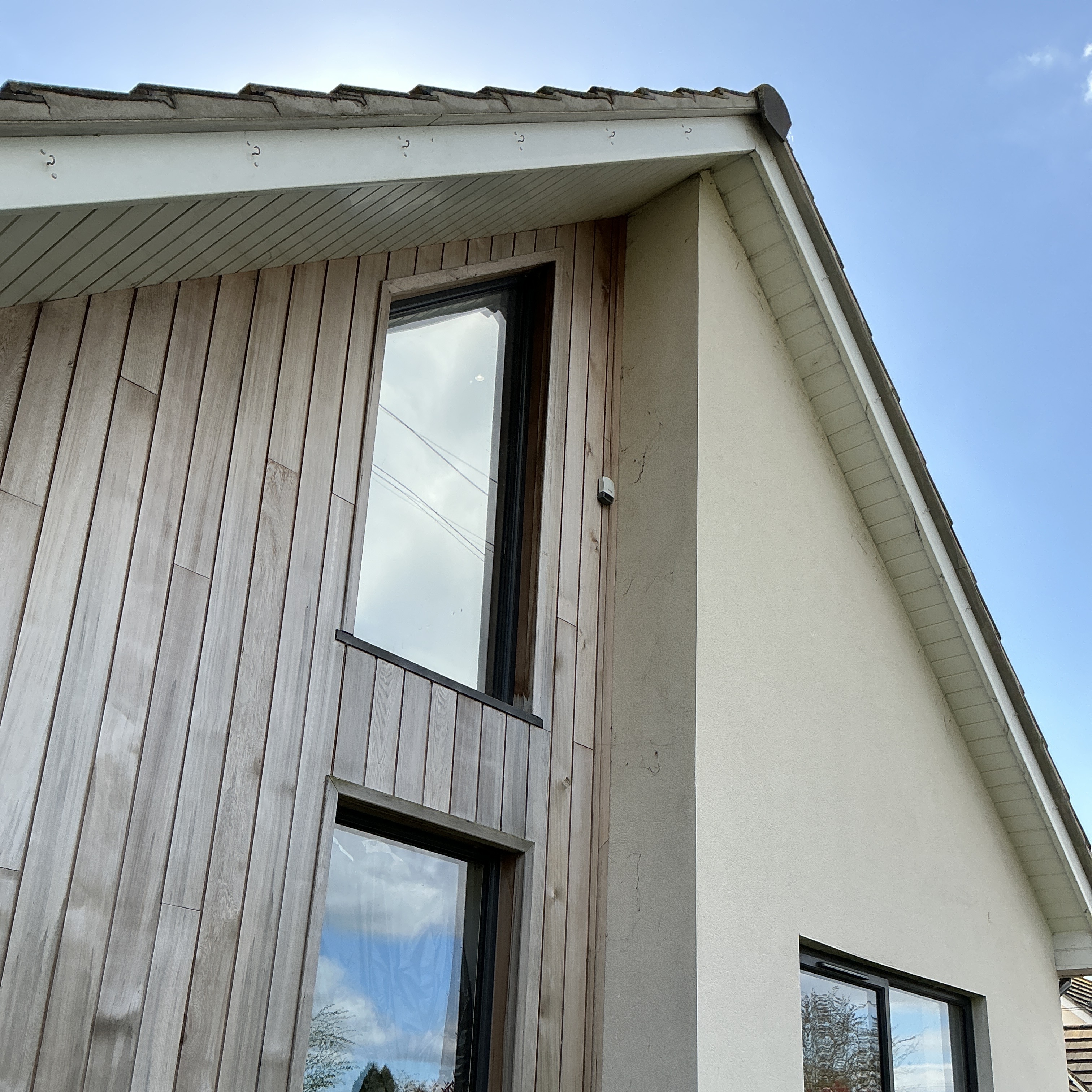 Vaillant outdoor temperature sensor mounted high on timber cladding beside an upstairs window